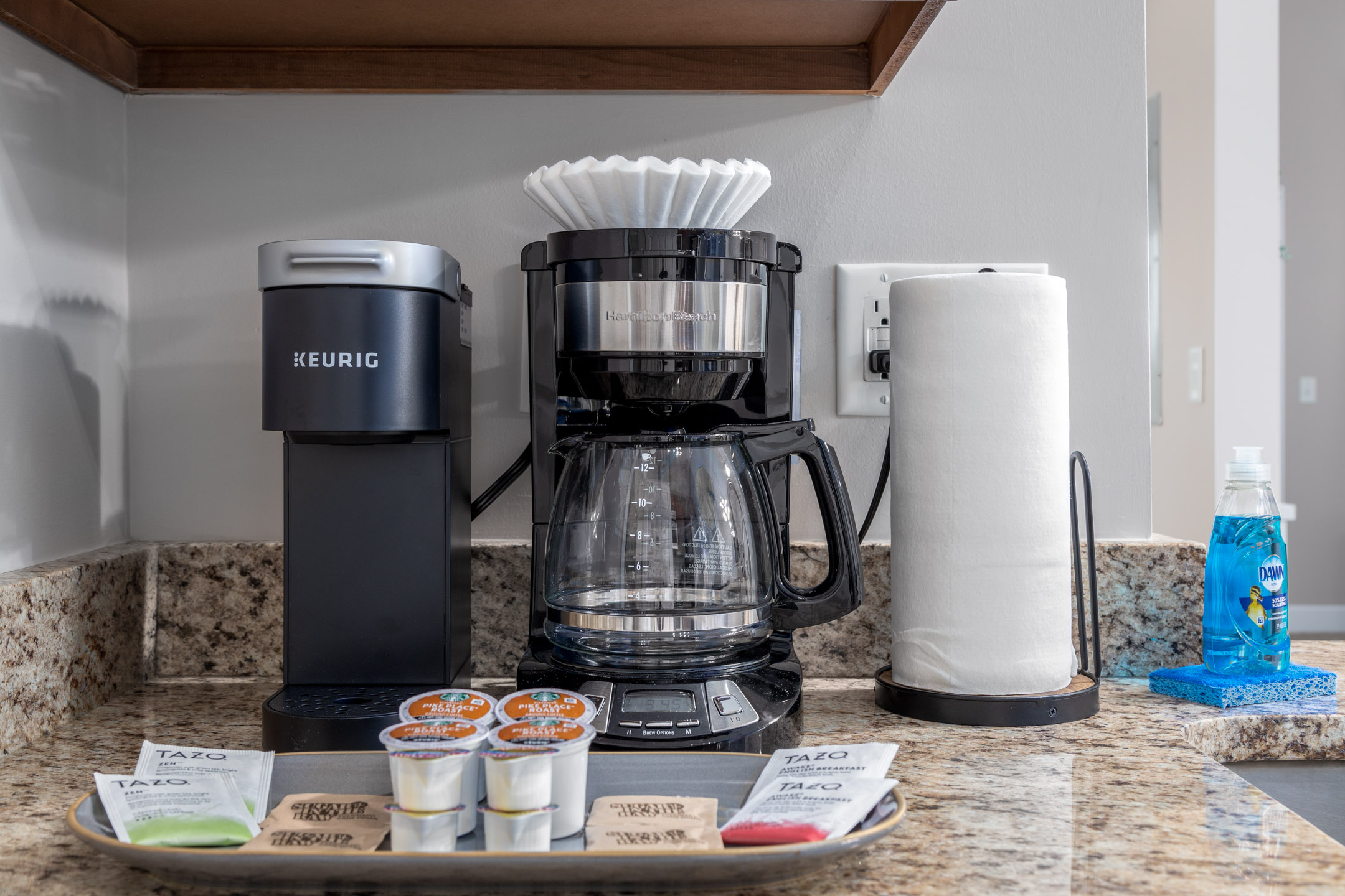 A drip coffee maker, Keurig, coffee, and tea supplies on the counter of a furnished apartment in Westerville Ohio