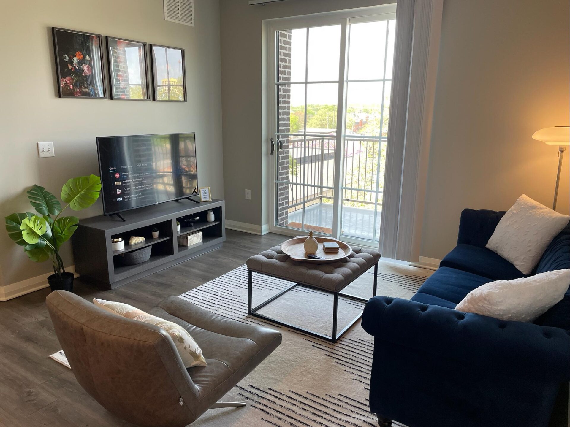 Living room with couch, coffee table, side chair, Smart TV, and large windows in a furnished apartment in Downtown Columbus