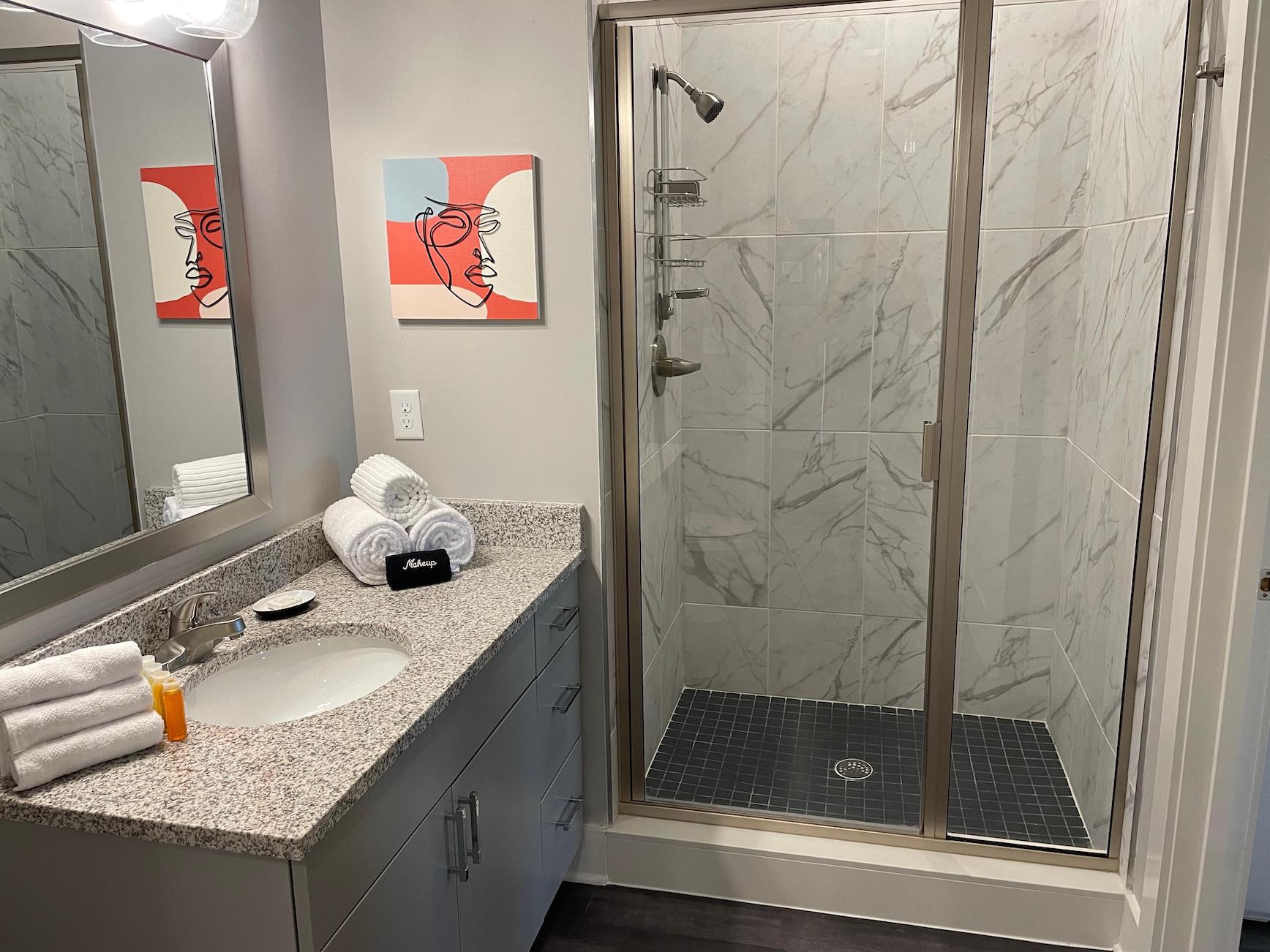 Clean bathroom with white towels and a walk-in shower in a furnished apartment near Ohio State