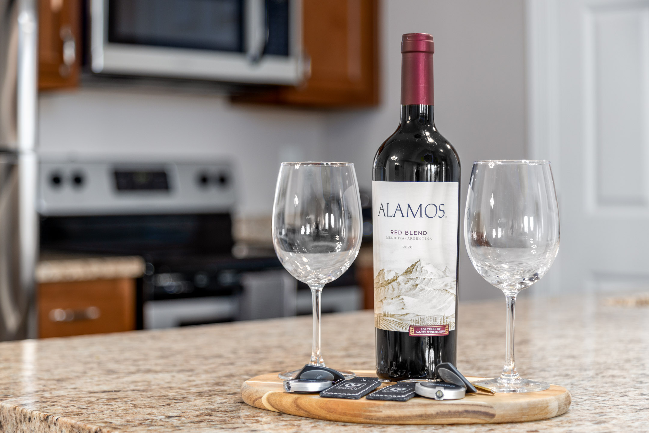 A bottle of wine and two clean wine glasses on the kitchen counter of a furnished apartment in Westerville Ohio