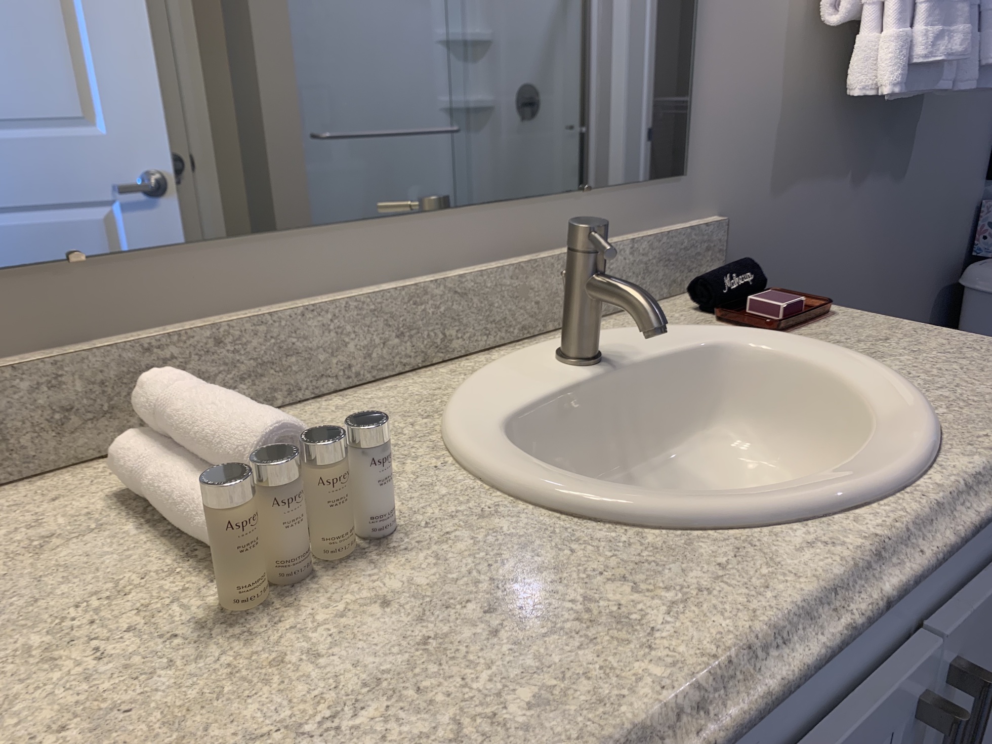 Bathroom vanity with toiletries, rolled wash cloths, and a soap dish in a furnished apartment in Downtown Columbus