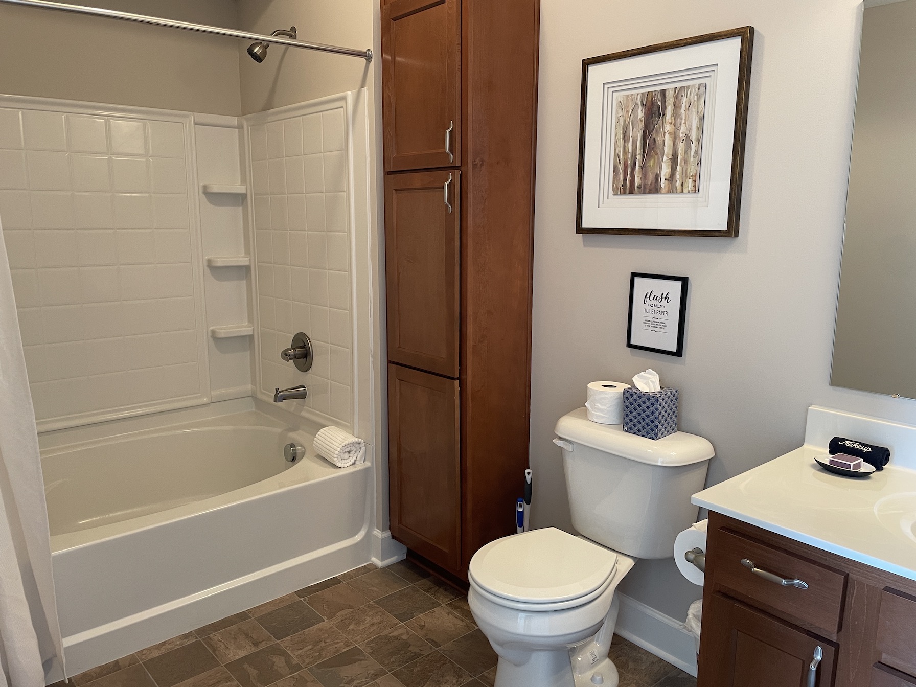 A clean bathroom with a shower tub combo, toilet, and vanity with mirror in a furnished apartment in Westerville Ohio